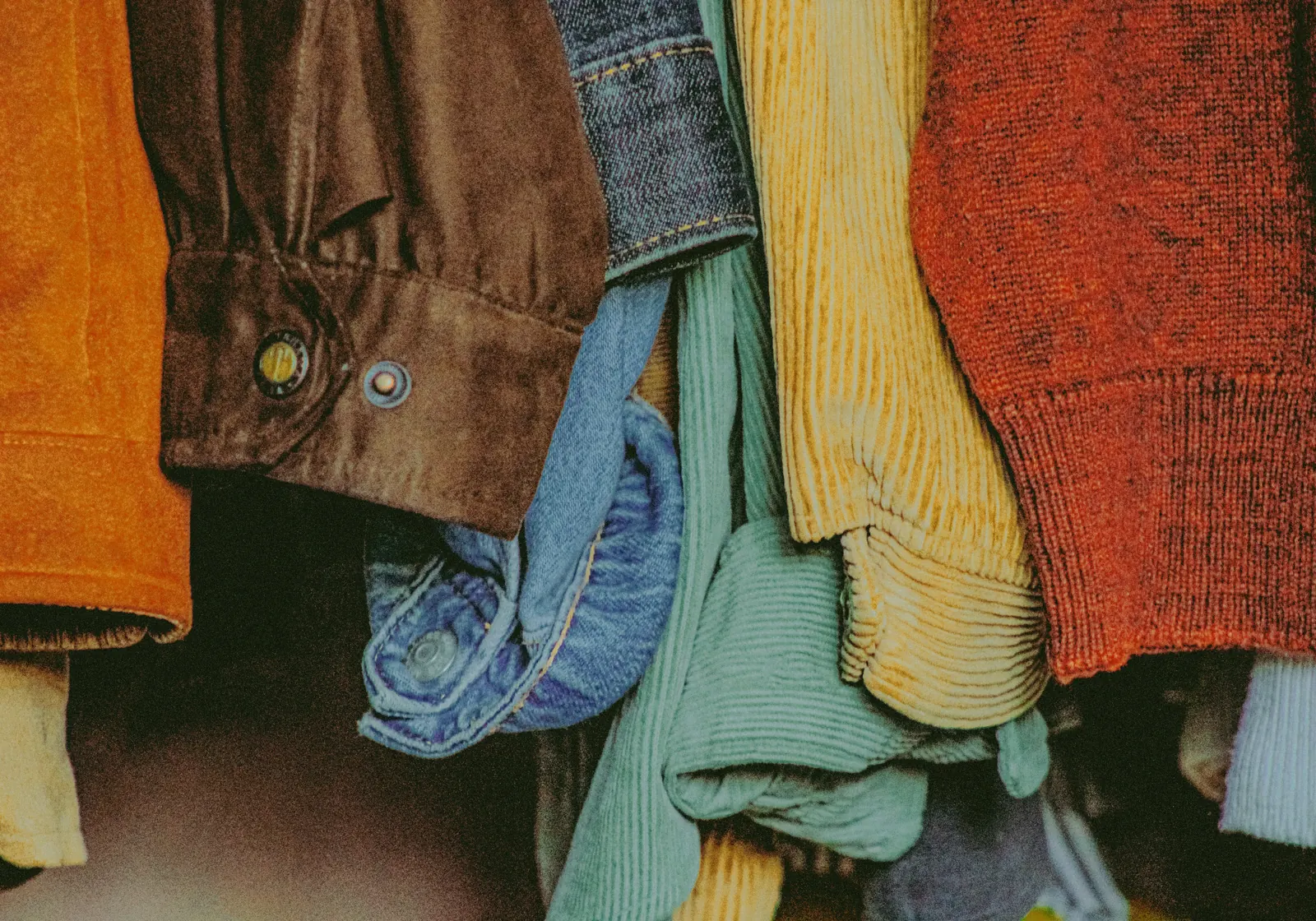 Close-up of worn jackets and knitwear hanging together